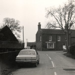 Sowbys Shop looking down Littlefield Lane from Sea Dyke Way. On the right of the photograph can just be seen the wooden bungalow that used to be there.  
Unfortunately the date of the photograph is unknown.