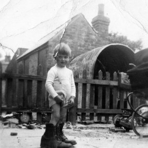 Ray Whiteley wearing his fathers hobnail boots.
This photograph was taken at the rear of Frank Whiteleys Butchers Shop on Sea Dyke Way, Marshchapel
The Fish and Chip Shop was on the other side of the fence and the small corrugated iron building seen in the background was used to house the potato "rumbler". This was filled with water and potatoes and turning the handle peeled them ready for chipping.