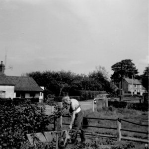Fred Grantham digging his garden at the side of his house "Sunnydene" in Church Lane.
In the background, on the right, can be seen "The Sycamores" which were subsequently rendered white and now demolished.
On the left is the cottage in front of the Village Hall.
This photograph was taken around 1957.
