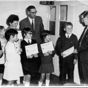 The teacher is Mr. Cockerill and it looks as if the children are being given their Cycling Proficiency Certificates.
The girl to the left of Mr Cockerill looks like Angela Welton.
The photograph could have been taken in the 1960s.