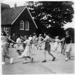 School Ring Game - c.1951
This game may have been "Waiting for a partner" when a boy went in first, chose a wife -much giggling from the rest. 
The wife then chose a child and the child chose a dog.
You were unlucky if you happened to be chosen as the last line of the song was "We all pat the dog" which could turn out to be quite painful".