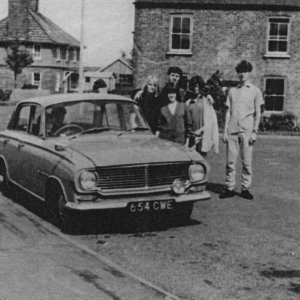 Early 60s Vauxhall Victor.
Photograph taken from Church Lane, looking across Sea Dyke Way towards the School House on the left.
The house in the centre was demolished for a road widening scheme which did not take place.
People in the picture, L to R; Judy Maguire, Gordon Horry, Jill Smith. The identities of the lad on the right, the girl in front and the occupants of the car are not known.