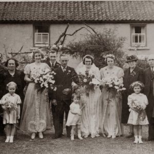 The wedding of Harry William Houlden and Eleaner Evison - 1943.
L to R; Joyce Clover, Dorothy Clover, "Uncle Bob", Granny Houlden, Dorothy "Doll" Wray, Morris Evison, Groom and Bride,
Unknown bridesmaid, Mr and Mrs Evison, Unknown, Mrs Evison holding young boy. Betty Clover "front right in coat", next to Desiree Clover "bridesmaid".
This photograph looks to be have taken outside the house in Church Lane, "which is sideways onto the road", where they lived.
Sadly Harry was killed at Cassino, Italy during WW2, on 5th. January 1944, aged 26.